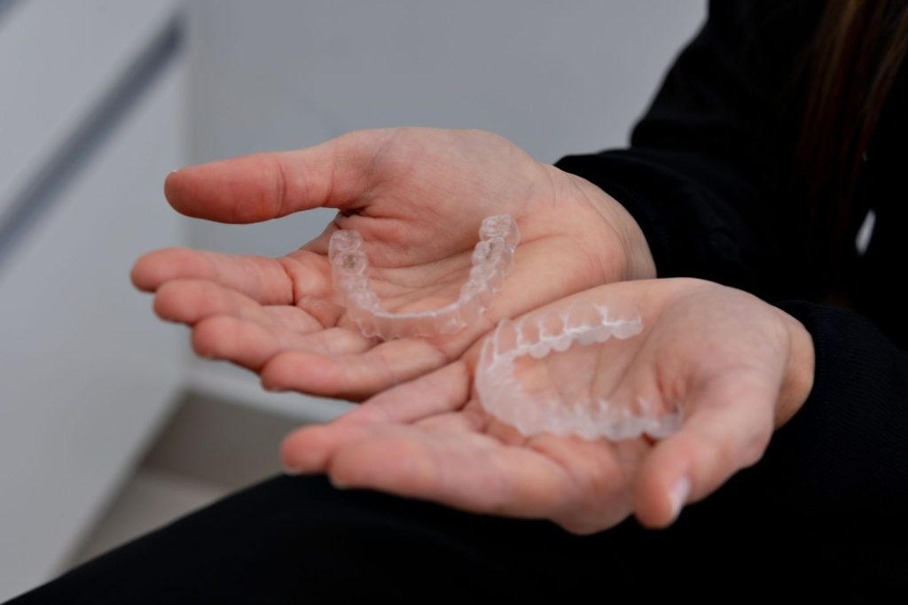 Clear Invisalign aligners held in a dental clinic